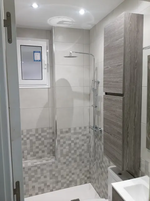 Baño con ducha de lluvia, zócalo de mosaico y columna de almacenaje gris
