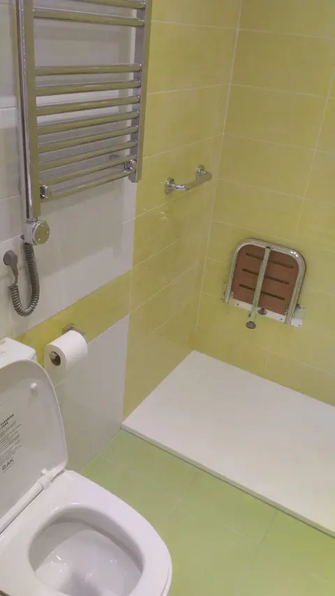 Ducha con asiento abatible de madera, barra de apoyo y toallero eléctrico