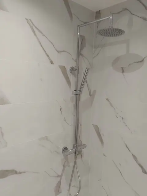 Ducha con revestimiento de efecto mármol veteado y columna de lluvia termostática