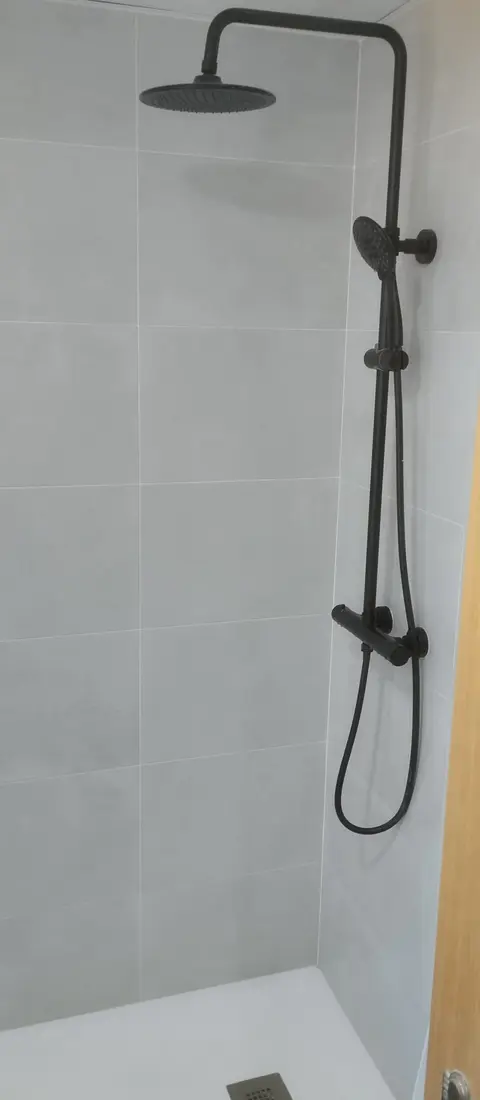 Ducha con columna de grifería negra y plato de ducha blanco