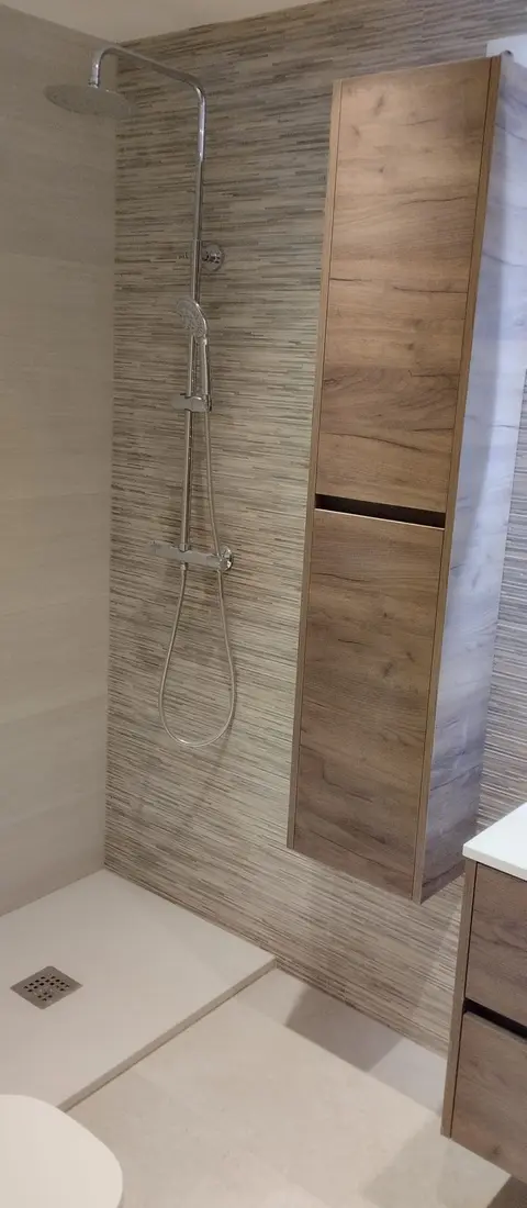 Ducha con plato blanco y columna de almacenaje de roble junto a la ducha