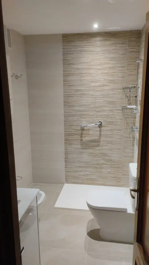 Ducha con plato blanco y pared del fondo revestida con relieve de listones