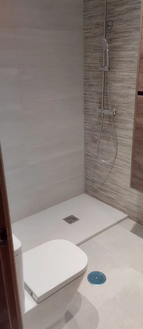 Ducha con plato blanco extraplano y revestimiento veteado de efecto madera